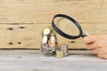 Analyzing personal savings or budget concept with jar full of money under the magnifying glass Royalty Free Stock Photo