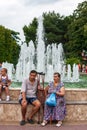 Aged disabled people sit together outdoors by fountain on sea embankment of Anapa city resort