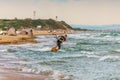 Anapa, Russia - July 9, 2017: Man kitesurfer rides kite through splashing waves by sandy shore of Black Sea. Popular kitesurf
