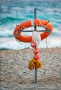 Safety lifebuoy with rope and childs cap put on cross against sea surf background. Spend vacations on sandy beaches of Anapa seasi