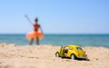 Anapa, Russia-July 2021: A small toy car stands on the beach with an open door against the background of the sea and the silhouett