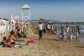 Donut seller walks between different people relaxing on the beach of the city of Anapa