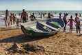 An empty lifeboat against the background of different people resting on the beach of the city of