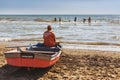Man sits in a boat on the shore of the Anapa beach and