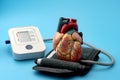 Anatomical model of human heart and digital blood pressure monitoring device (sphygmomanometer) in cardiologist office
