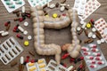 Anatomical model of large intestine and many different pills on wooden background, flat lay
