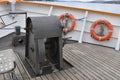 Anchor gear fixed on wooden boarder floor in bow of a tourist cruiser ship painted white.