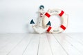 Anchor and life buoy on a white wooden floor