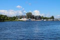 Anchorage of yachts by the river bank against the background of houses and a blue sky with clouds. St. Petersburg