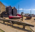 Anchors, net drying sheds and Fishing boats beneath a blue sky at Hastings, Sussex, UK Royalty Free Stock Photo