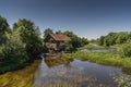 Ancient abandoned water mill surrounded by beautiful nature. House built of stone and wood, exterior walls and dilapidated bridge Royalty Free Stock Photo