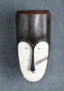 An ancient african wooden mask isolated over a gray background. Face mask of the ngil society, Gabon Africa