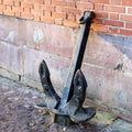 Ancient anchor stands on the ground leaning against the wall