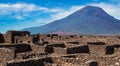 ancient archeology of stone houses with a volcano in the background