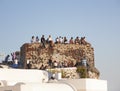 Santorini, Greece - June 05 2012: Tourists sit on an old ruined wall waiting for the sunse