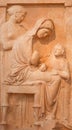 Ancient bas-relief depicting young seated woman with boy and maiden stands in background on ancient Greek funerary stele from