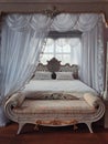 Ancient bedroom furniture style, medieval king bed, near the window, white curtains canopy and gold details. Close up background Royalty Free Stock Photo