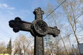 Ancient black iron forged cross banked among the sky in the Troitskoye cemetery 1842 of Krasnoyarsk city, in the spring
