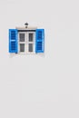 Ancient blue window is open on a white concrete wall, with old style lamp black frame on top. Royalty Free Stock Photo