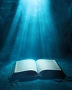 Ancient book illuminated by ethereal light in dark cavern Royalty Free Stock Photo