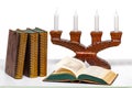 Ancient books and below an open book in front of an antique wooden candlestick on a light table isolated on a white background Royalty Free Stock Photo