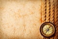 Ancient brass compass with rope on vintage old paper background. Retro stale.