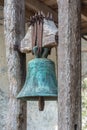 Ancient bronze bell covered with patina hanging from a wooden structure