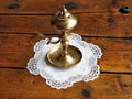 Ancient bronze oil lamp in a white cloth embroidered on a rustic wooden table. Royalty Free Stock Photo