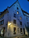 An ancient building with an arched entrance and a beautiful, original lantern on the corner in the city center against the blue