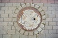 Ancient cast iron rusty manhole on pavement sidewalk of city street Royalty Free Stock Photo