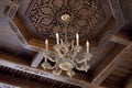 Ancient chandelier on wooden carving ceiling background. Travel