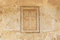 Ancient Christian cross engraved in a yellow beige limestone wall.Close-up of the bas-relief on the old vintage surface.religion c Royalty Free Stock Photo