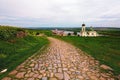 Ancient cobblestone road through the hills with green grass to the medieval castle. Picturesque spring landscape. Royalty Free Stock Photo