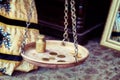 Ancient coins with a weight on the scales. Vintage interior of a wooden house. The bowl of the big scales hangs on chains