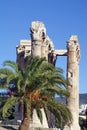 Ancient columns with a lintel behind a palm tree