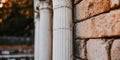 Ancient columns stand beside rustic brick wall in tranquil outdoor setting during sunset Royalty Free Stock Photo