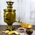 Ancient copper samovar on a wooden table with a Cup of tea breadcrumbs biscuits jam. Royalty Free Stock Photo