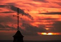 Ancient cross on a church in red sunset