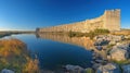 Ancient dam reflecting on calm lake, sunrise Royalty Free Stock Photo