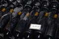 Ancient dark dusty wine bottles aging in underground cellar in rows. Concept winery vault with rare wines, exclusive