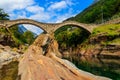 Ancient double arch stone Roman bridge (Ponte dei Salti) over clear water of the Verzasca river Royalty Free Stock Photo