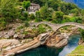 Ancient double arch stone Roman bridge (Ponte dei Salti) over clear water of the Verzasca river in Lavertezzo Royalty Free Stock Photo