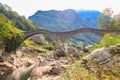 Ancient double arch stone Roman bridge (Ponte dei Salti) over clear water of the Verzasca river in Verzasca Valley Royalty Free Stock Photo