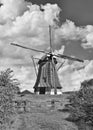 Ancient windmill with thatched roofing in a field with dramatic shaped clouds, The Netherlands