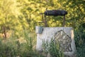 Ancient draw-well in European village, Old Water Well With Pulley and Bucket, Moldova, Green grass and trees. Sunny day. sunset