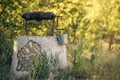 Ancient draw-well in European village, Old Water Well With Pulley and Bucket, Moldova, Green grass and trees. Sunny day. sunset Royalty Free Stock Photo