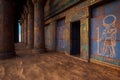 Ancient Egyptian temple or tomb entrance surrounded by blue and gold painted columns and walls. 3D illustration