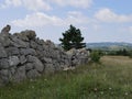 An ancient fence made of huge stones in the mountains of Crimea against the blue sky with white Cumulus clouds on a Sunny summer . Royalty Free Stock Photo