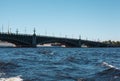 Ancient forged bridge above blue waves of Neva river