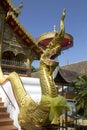 Ancient golden serpent statue in front of the stairs of a Thai temple